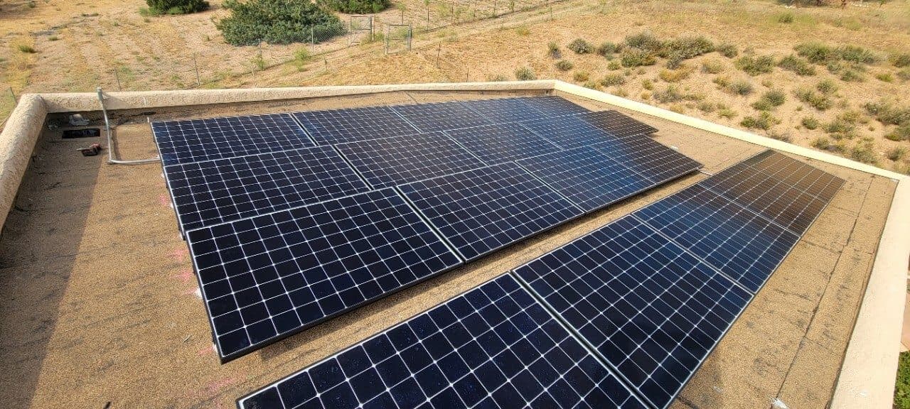 Large parapet-mounted solar array on a low-slope roof in the high desert of Acton, CA