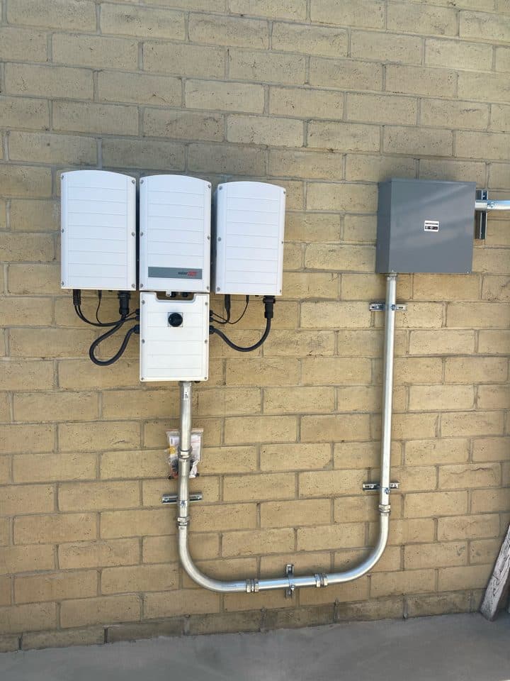 Three SolarEdge three-phase inverters wall-mounted at a commercial solar installation in Anaheim, CA