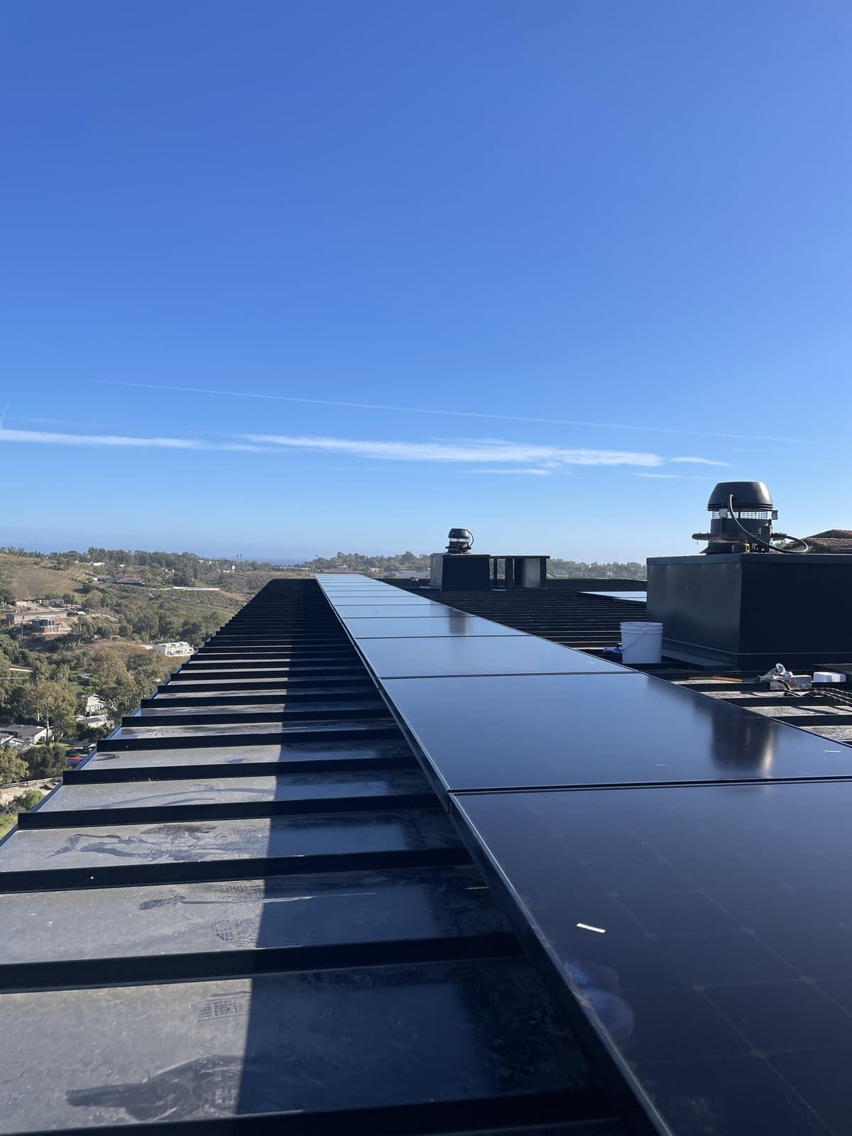 All-black solar panel array along a Malibu, CA ridgeline roof with an ocean view