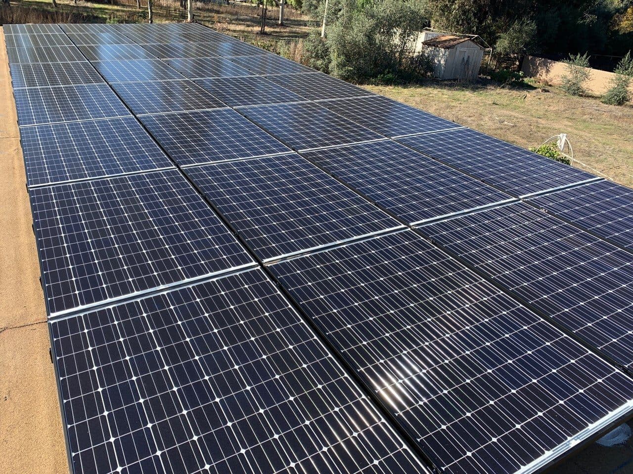 Large high-production solar array on a low-slope roof of a rural property in San Marcos, CA